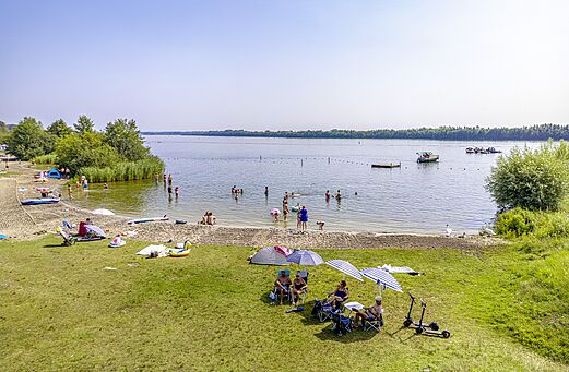 Zandstrand met zwemmen en wateractiviteiten op camping CAPFUN Erkemederstrand in Zeewolde.