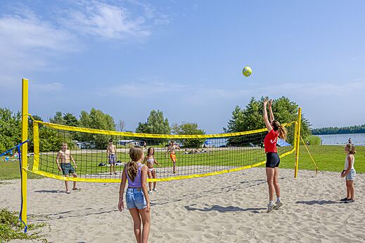 Beachvolleybalwedstrijd op het strand met kinderen op camping CAPFUN Erkemederstrand in Zeewolde.