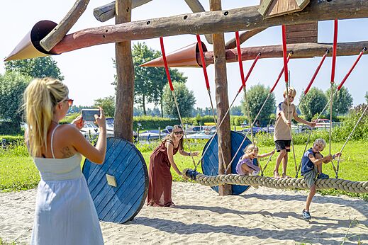 Houten en touw speeltuin met kinderen op camping CAPFUN Erkemederstrand in Zeewolde.