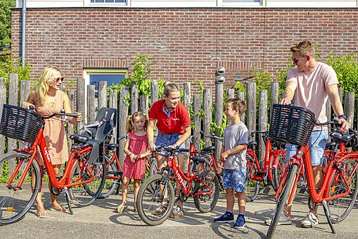 Familie huurt rode fietsen met kinderzitje op camping CAPFUN Erkemederstrand in Zeewolde.