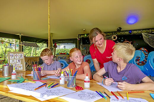 Kinderen kleuren met animator tijdens activiteit op camping CAPFUN Erkemederstrand in Zeewolde.