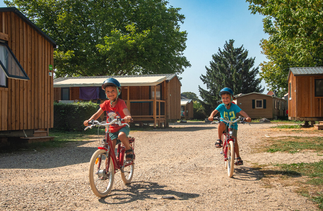 Twee kinderen op fietsen op campingpad, VAGUES OCEANES Lac d'Erstein (67).