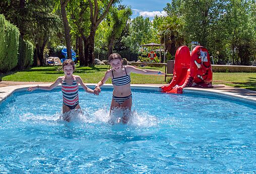 Twee kinderen spelen in het zwembad met glijbaan op camping CAPFUN El Escorial in El Escorial, Madrid.