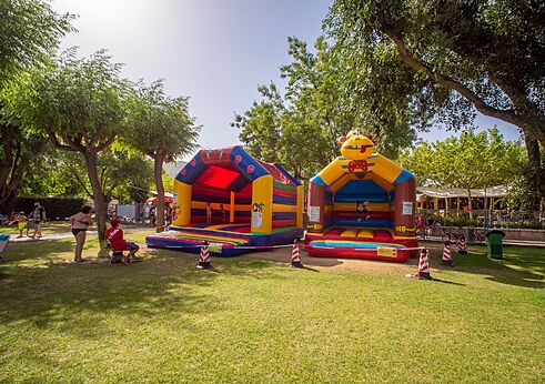 Twee kleurrijke opblaasbare springkastelen voor kinderen op camping CAPFUN El Escorial in El Escorial, Madrid.