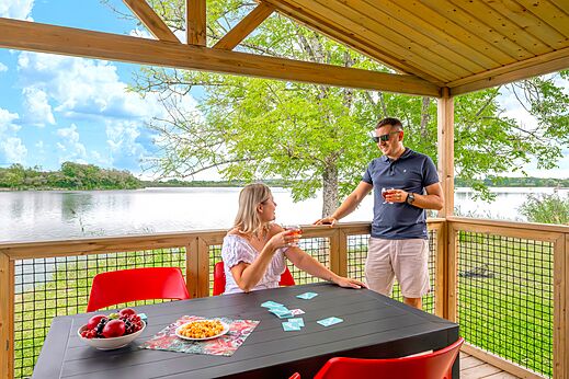Koppel op accommodatieterras met uitzicht op het meer op camping CLICOCHIC Etang de la Mutche in HARPRICH (57).