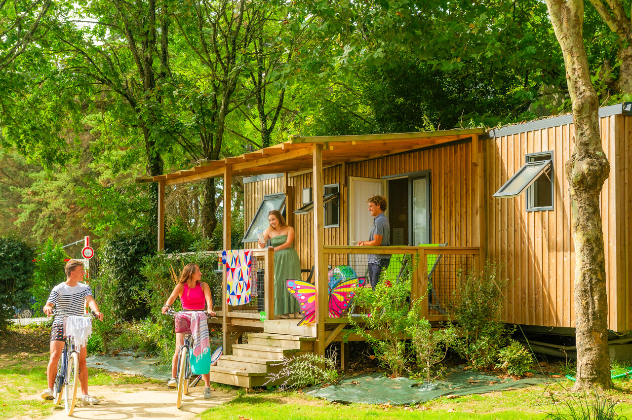 Houten stacaravan, terras, jongeren met fiets bij CAPFUN L'Eve (44).