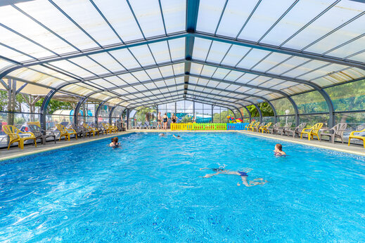 Verwarmd overdekt zwembad met zwemmers en stoelen op camping CAPFUN L'Eve in Saint-Marc-sur-Mer (44).