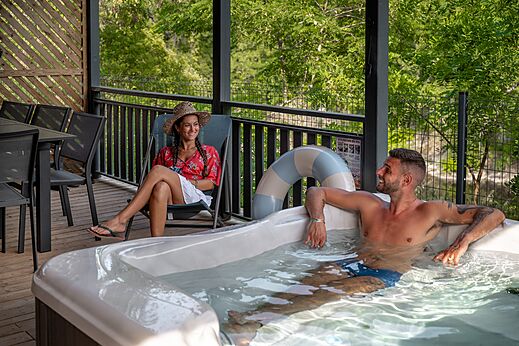 Koppel genietend van privé jacuzzi op terras op camping CLICOCHIC Eyrieux.
