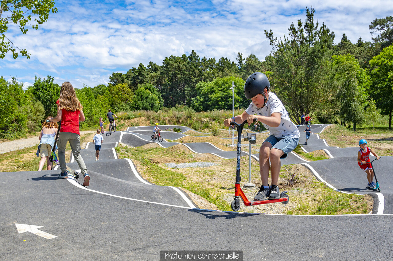 Kinderen op pumptrack met scooters en fietsen op camping CAPFUN Falaises in Gonneville sur Mer.