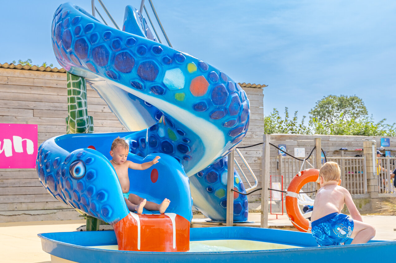 Kinderen spelen op de blauwe waterglijbaan op camping CAPFUN Falaises in Gonneville sur Mer.