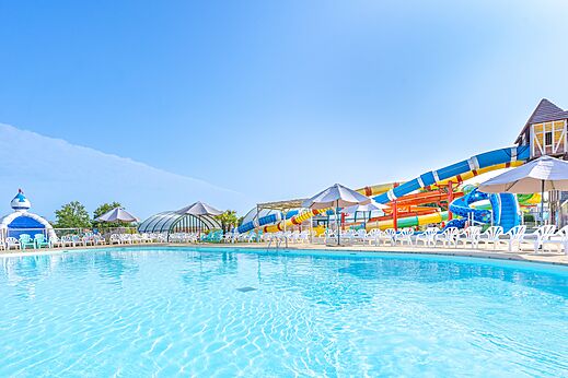 Buitenzwembad, waterglijbanen en stoelen op camping CAPFUN Falaises in Gonneville sur Mer (14).