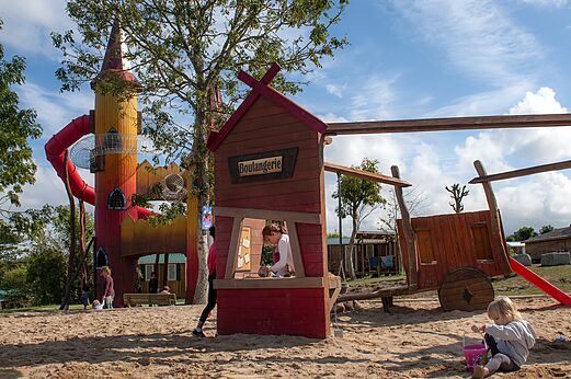 Speeltuin met kleurrijke toren, glijbaan en speelhuisje op camping CAPFUN Falaises in Gonneville sur Mer (14).