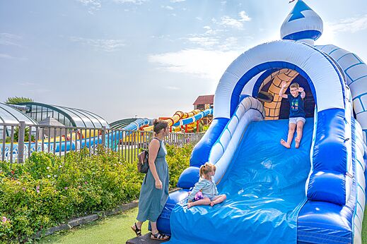 Grote opblaasbare glijbaan en spelende kinderen op camping CAPFUN Falaises in Gonneville sur Mer (14).