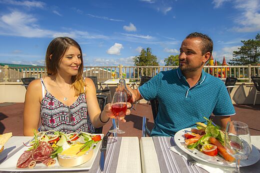 Koppel dineert op terras bij restaurant van camping CAPFUN Falaises in Gonneville sur Mer.
