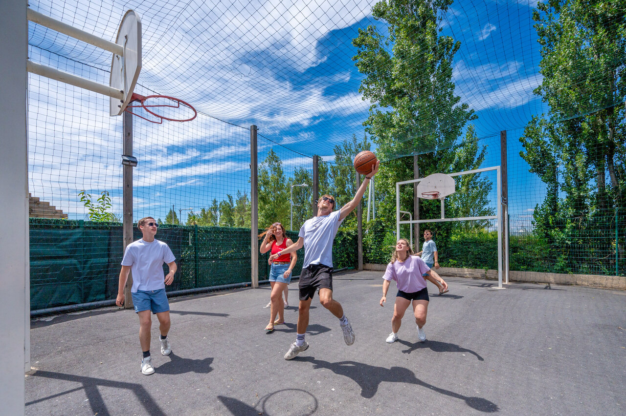 Jongeren basketballen op multisportterrein bij CAPFUN F�erix MARSEILLAN PLAGE.