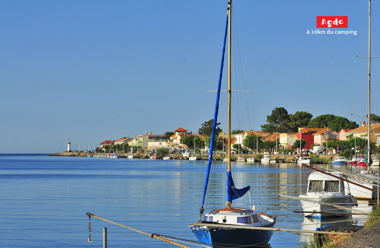 Haven van Agde met zeilboten, kleurrijke huizen en vuurtoren, te bezoeken nabij Marseillan Plage.