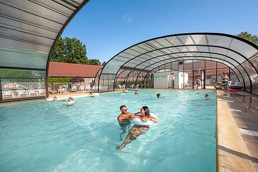 Overdekt en openlucht zwembad met zwemmers op camping CLICOCHIC Ferme des Aulnes NAMPONT SAINT MARTIN.