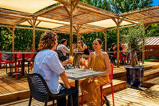 Lachend stel genietend van cocktails op het barterras op camping CLICOCHIC Filament in Thoiras (30).