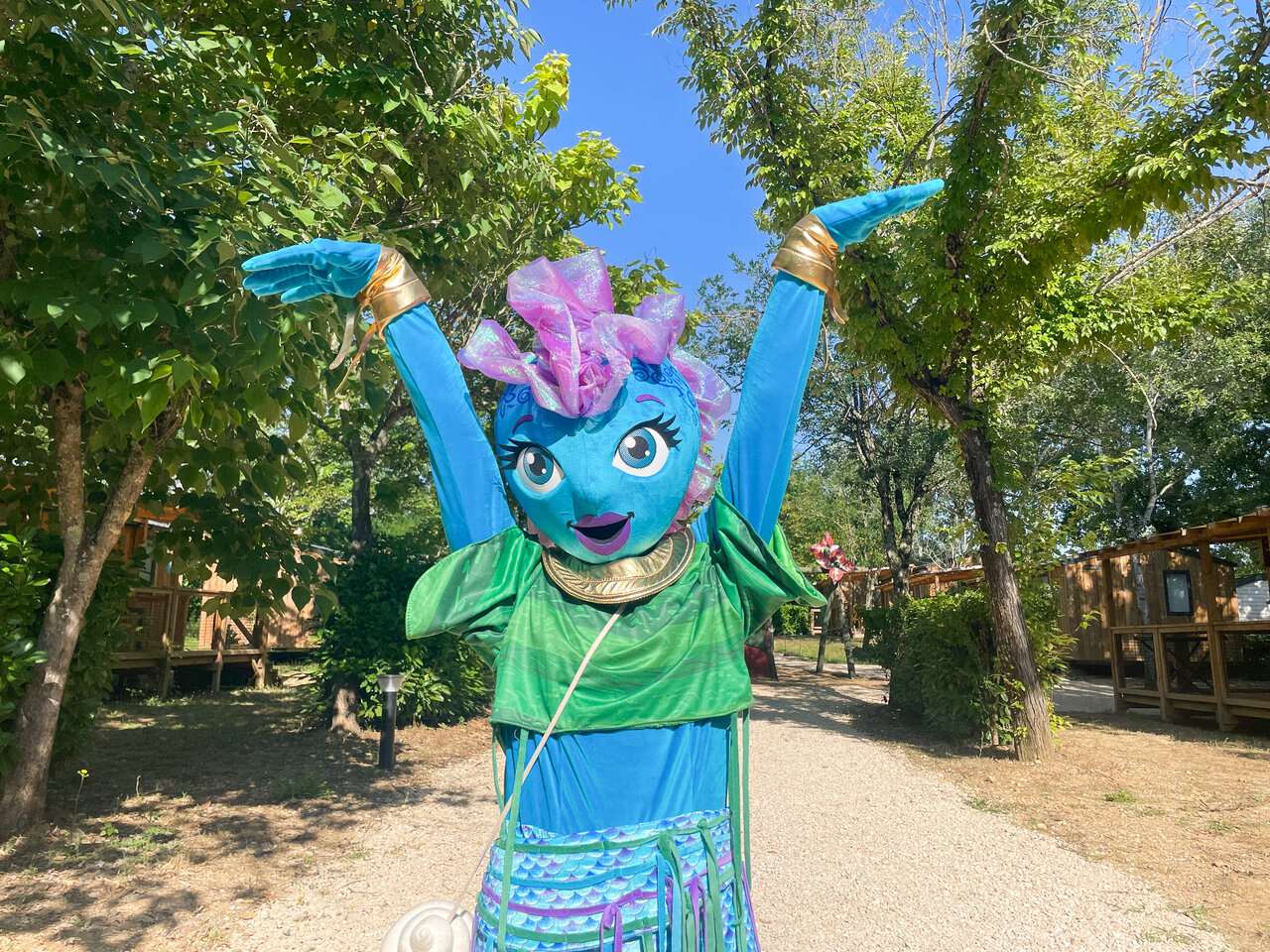 Lachende blauwe mascotte met opgeheven armen voor stacaravans op camping VAGUES OCEANES Au Flamenco in Argel�s-sur-Mer (66).