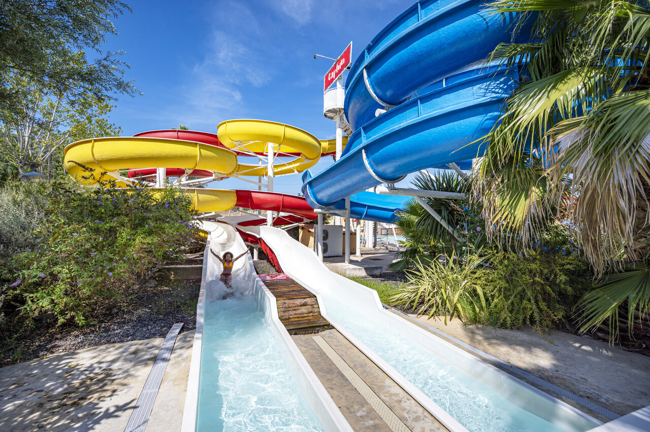 Meerkleurige waterglijbanen, kind heeft plezier op camping CAPFUN Fleurs d'Agde in AGDE (34).