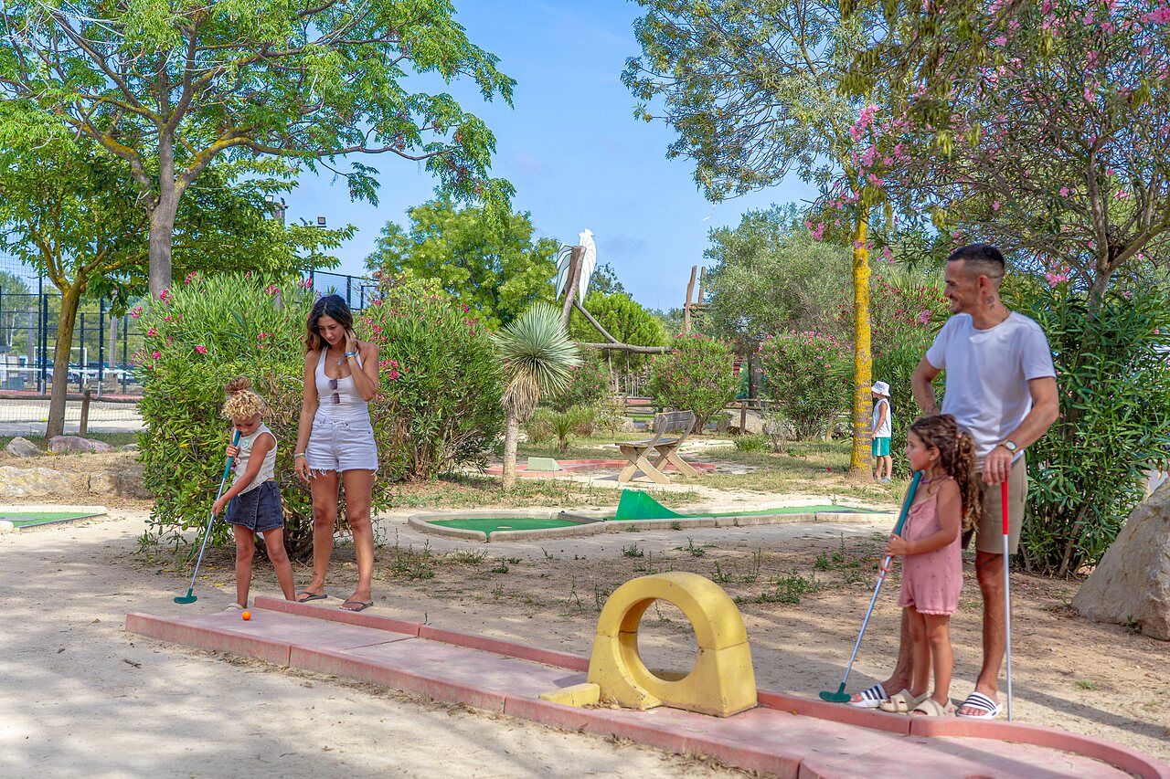 Familie speelt minigolf op een buitenbaan op camping CAPFUN Fleurs d'Agde in AGDE (34).