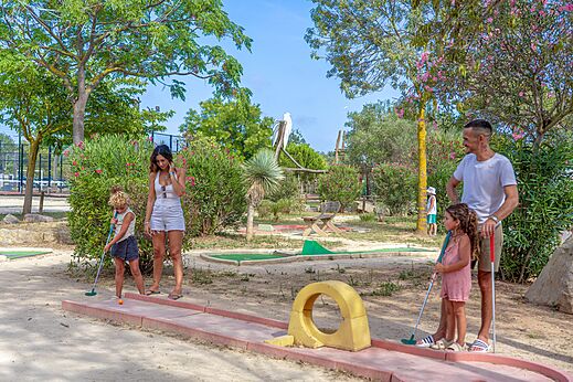 Familie speelt minigolf op een buitenbaan op camping CAPFUN Fleurs d'Agde in AGDE (34).