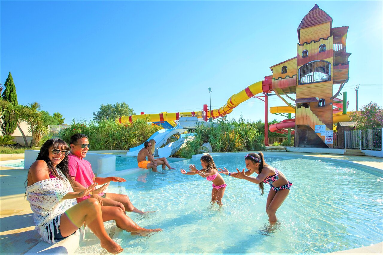 Zwembad met waterglijbanen, kasteelstructuur en familie op camping CAPFUN Fleur de Camargue in Saint-Laurent-d Aigouze (30).