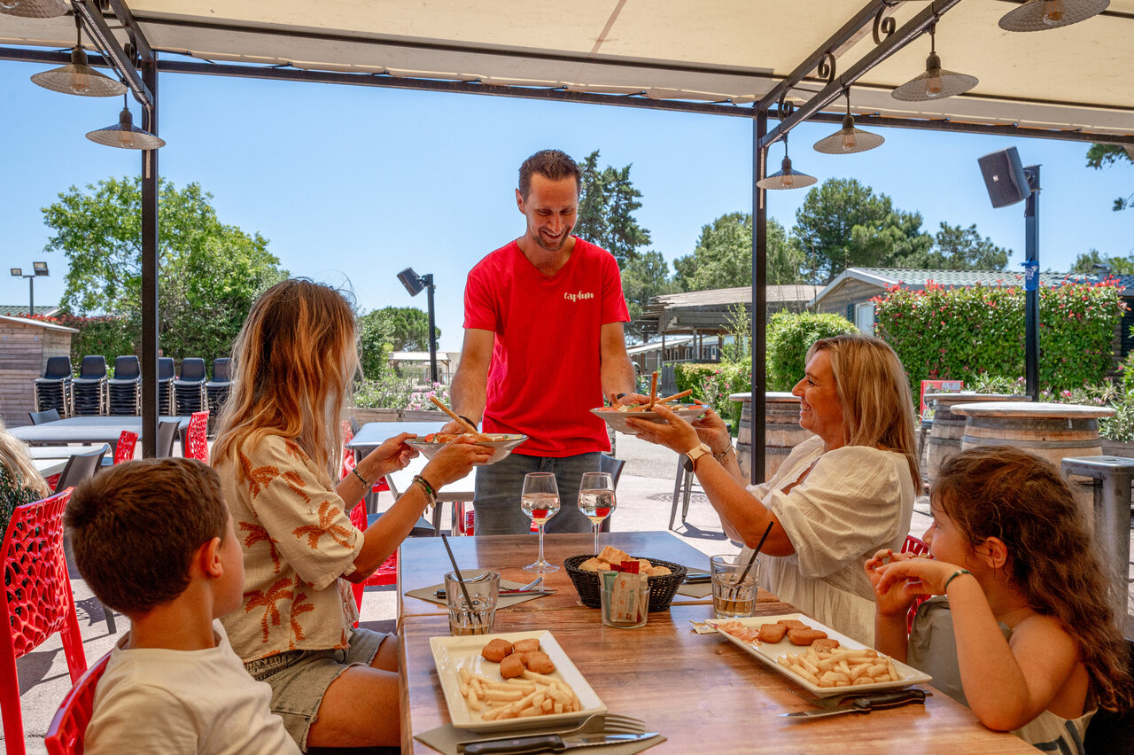 Familie eet buiten op camping CAPFUN Fleur de Camargue in Saint-Laurent-d Aigouze.