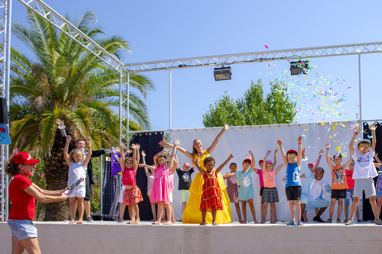 Vrolijke kinderen en animatoren op podium met confetti op camping CAPFUN Fleur de Camargue in Saint-Laurent-d Aigouze (30).