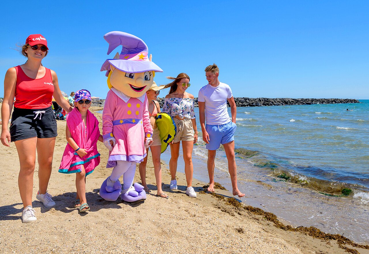 Mascotte en vakantiegangers op strand bij camping CAPFUN Flots Bleus, VIAS PLAGE.