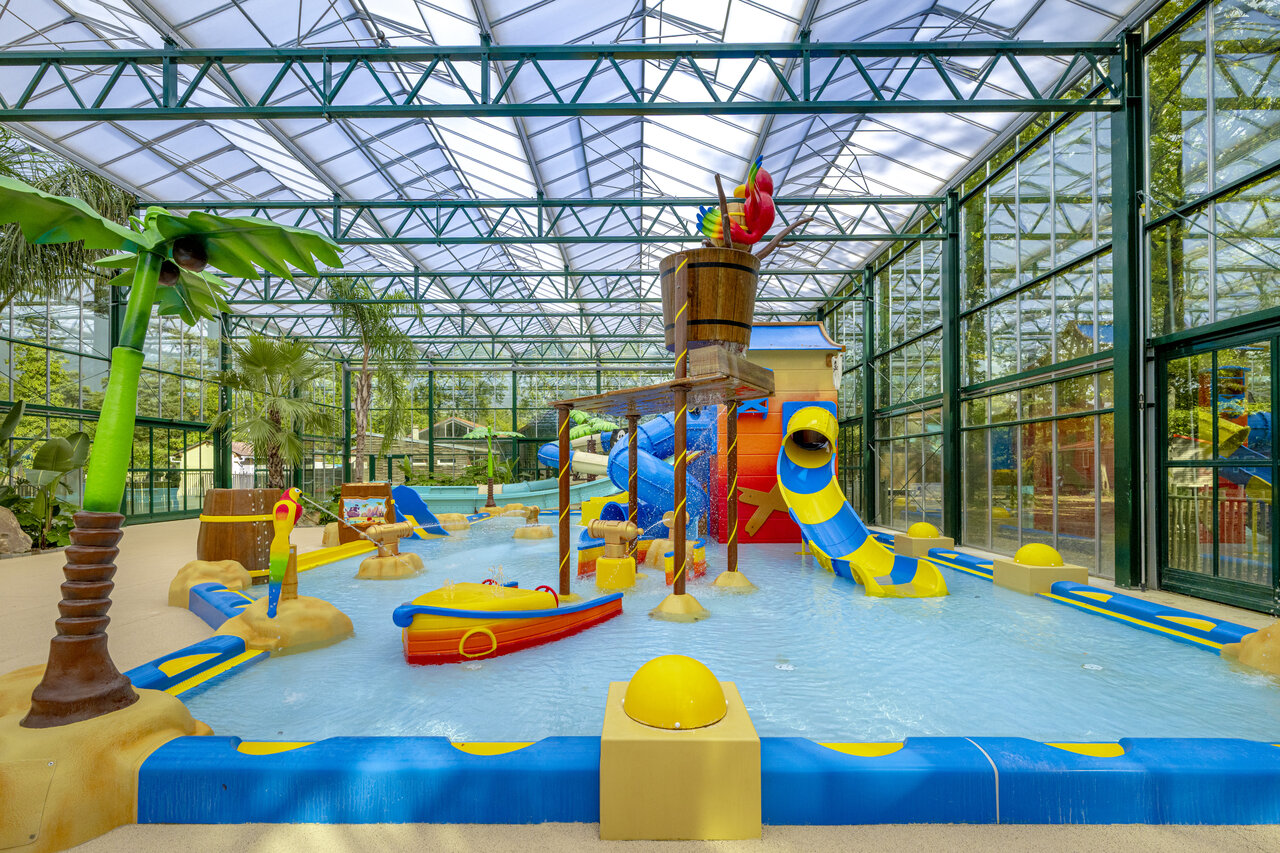 Overdekte waterspeeltuin met glijbanen en kantelende emmer op camping CLICOCHIC La For�t d'Azal�e in Saint-Ch�ron (91).