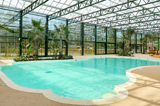 Verwarmd binnenzwembad met palmbomen op camping CLICOCHIC La For�t d'Azal�e.