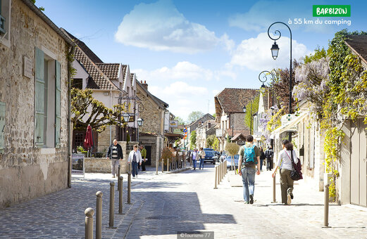 Geplaveide straat in het dorp Barbizon, Seine-et-Marne, met historische huizen en voorbijgangers.