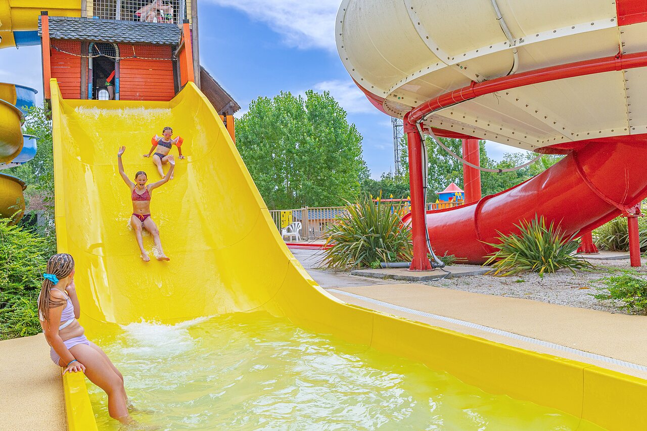 Gele waterglijbaan en zwembad met kinderen op camping CAPFUN Forges in Avrille (85).