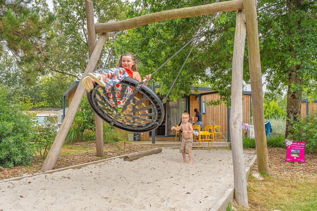 Kinderen spelen op nestschommel en zandbak op camping CAPFUN Forges in Avrille (85).