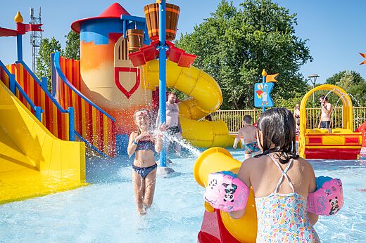 Waterspeeltuin met glijbanen en lachende kinderen op camping CAPFUN Forges in Avrille (85).