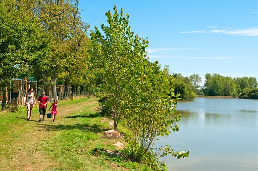 Familie vist aan de oever van het natuurlijke meer op camping CAPFUN Forges in Avrille (85).