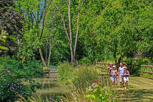 Familie wandelt langs rivier, weelderige natuur op camping CLICOCHIC Forge Sainte Marie.