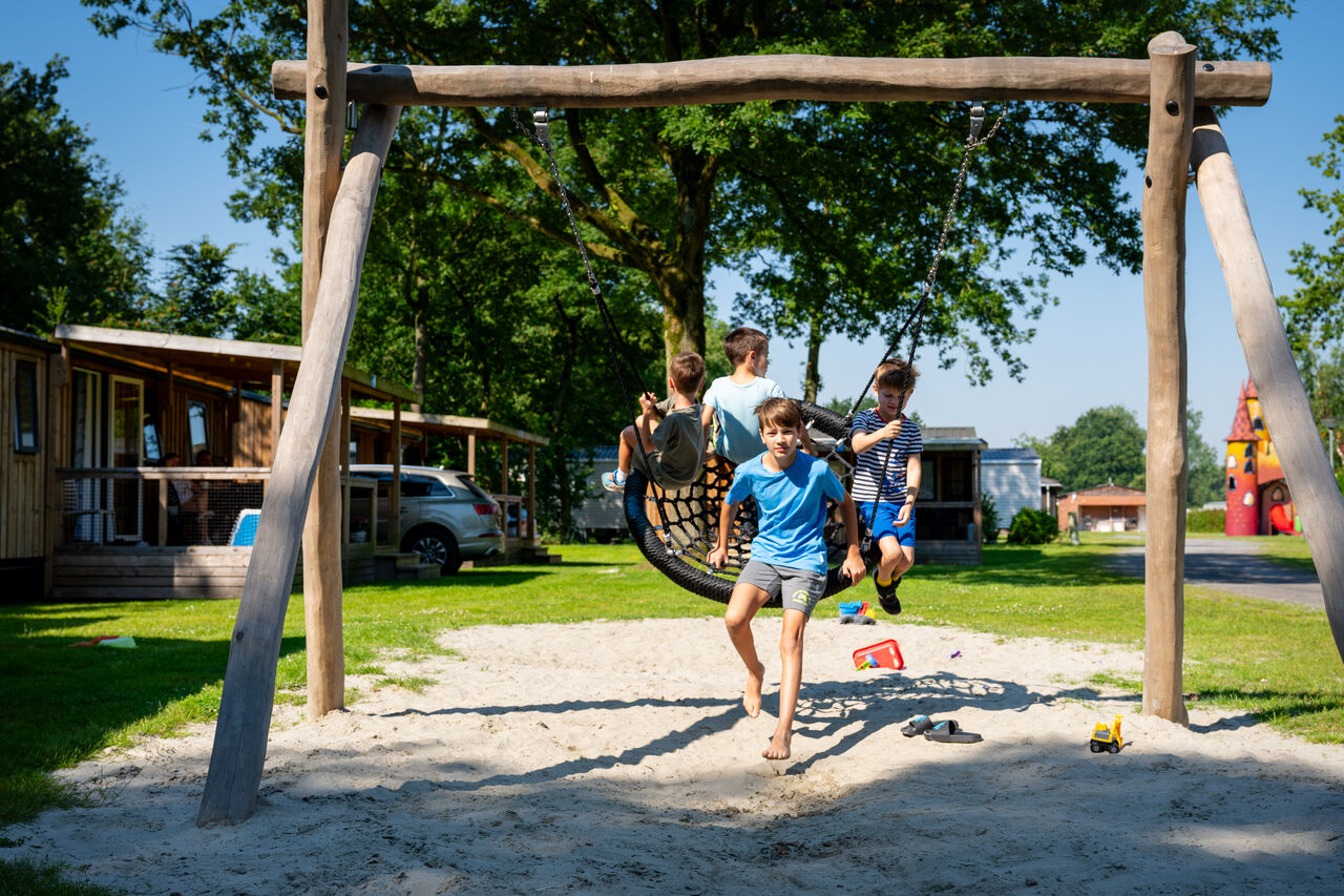 Kinderen spelen op vogelnestschommel, speeltuin op camping CAPFUN Fort Bedmar.