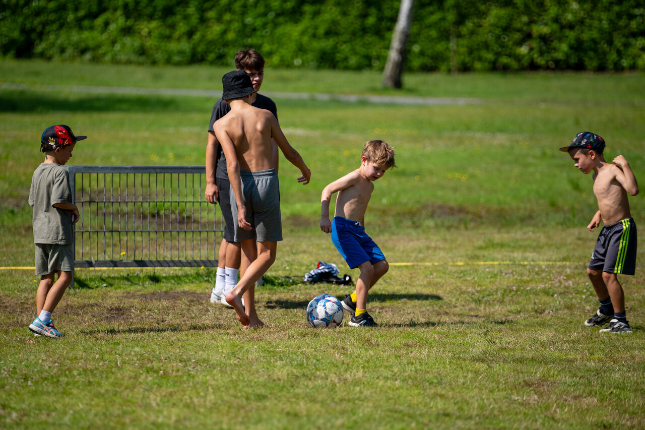 Kinderen voetballen op een sportveld op camping CAPFUN Fort Bedmar in Sint-Gillis-Waas.