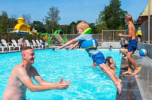 Kind springt in zwembad met volwassene op camping CAPFUN Fort Bedmar in Sint-Gillis-Waas