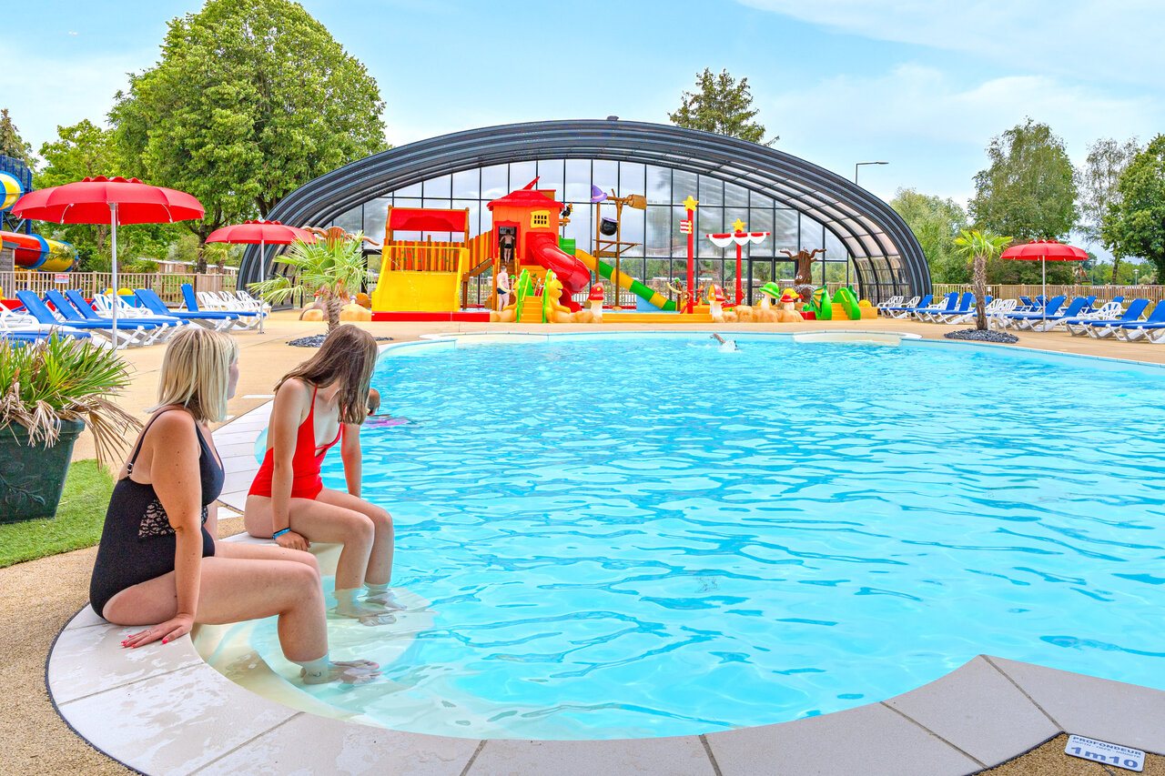 Twee vrouwen bij zwembad met waterpark in camping CAPFUN Fort Falabraque in Seltz (67).