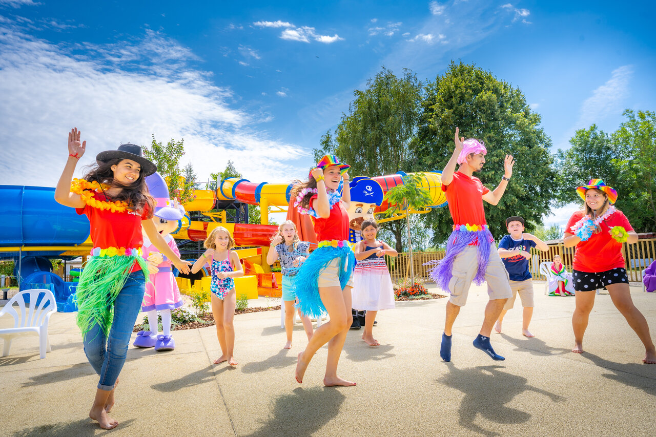 Animators en kinderen dansen vrolijk bij de waterglijbanen op camping CAPFUN Fort Falabraque in Seltz (67).