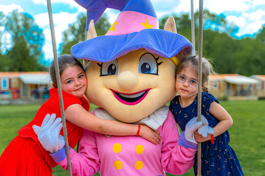 Twee meisjes knuffelen een vrolijke mascotte op camping CAPFUN Fredland in Tournan en Brie (77).