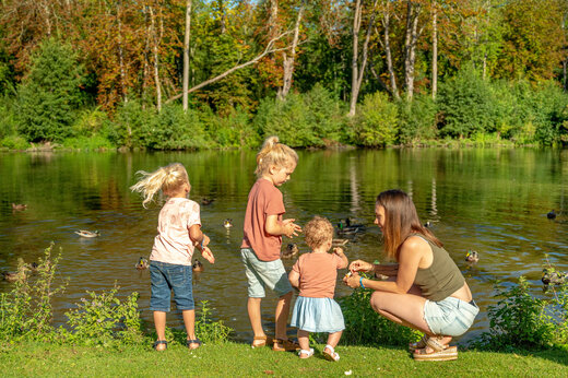 Familie voedt eenden aan de oever van een meer op CAPFUN Fredland.