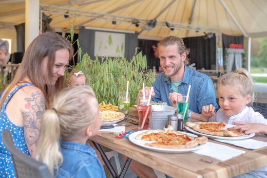 Lachende familie eet pizza's in het restaurant van camping CAPFUN Fredland in Tournan en Brie (77).