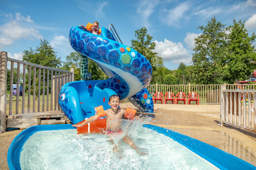 Speelse waterglijbaan en kinderen spelend in het zwembad op camping CAPFUN Fredland in Tournan en Brie (77).