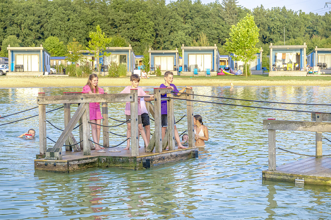 Kinderen spelen op drijvend platform in meer, accommodaties op camping CAPFUN De Fruithof in Klijndijk.