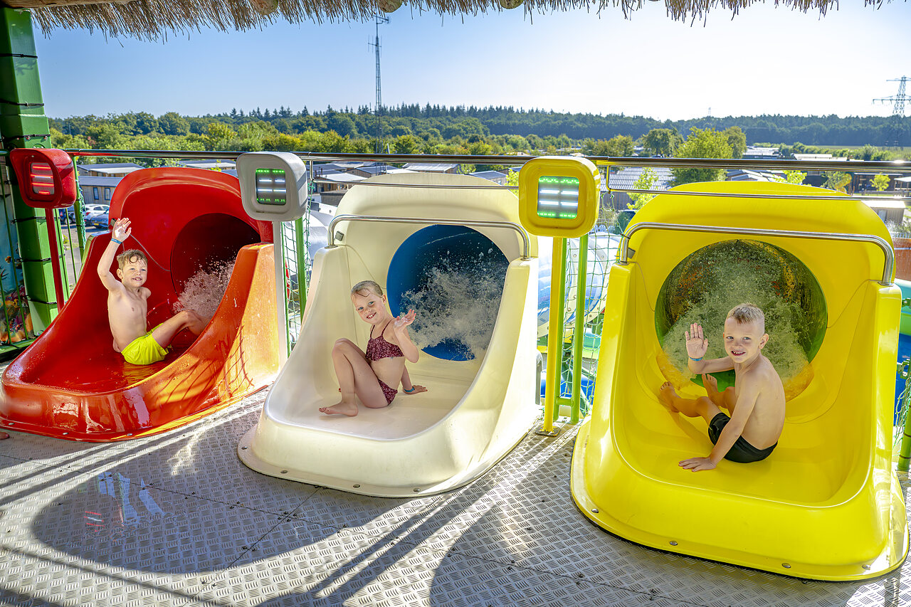 Lachende kinderen op de kleurrijke waterglijbanen van camping CAPFUN De Fruithof in Klijndijk.