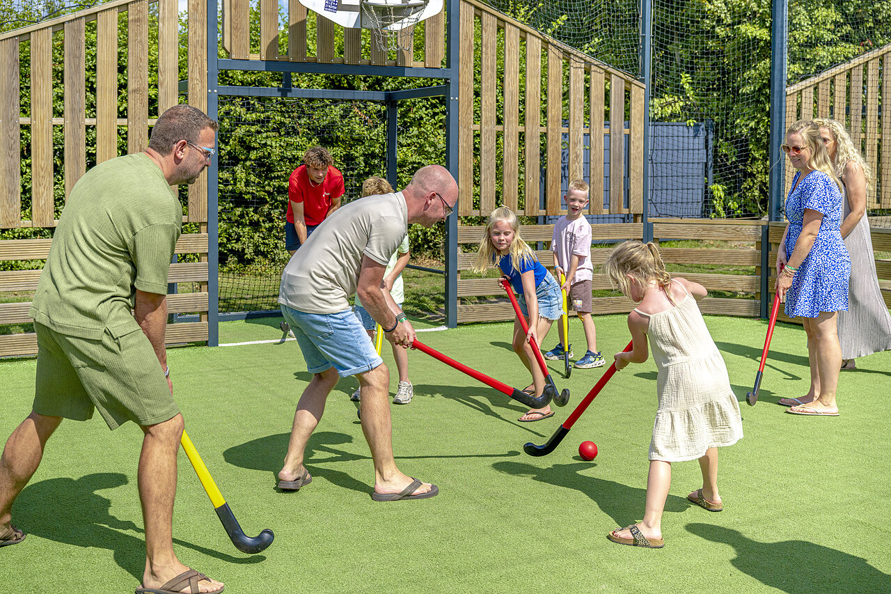 Familie speelt hockey op kunstgrasveld op camping CAPFUN De Fruithof in Klijndijk.